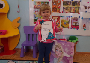 Dziewczynka prezentując dyplom za udział w konkursie "Choinka"